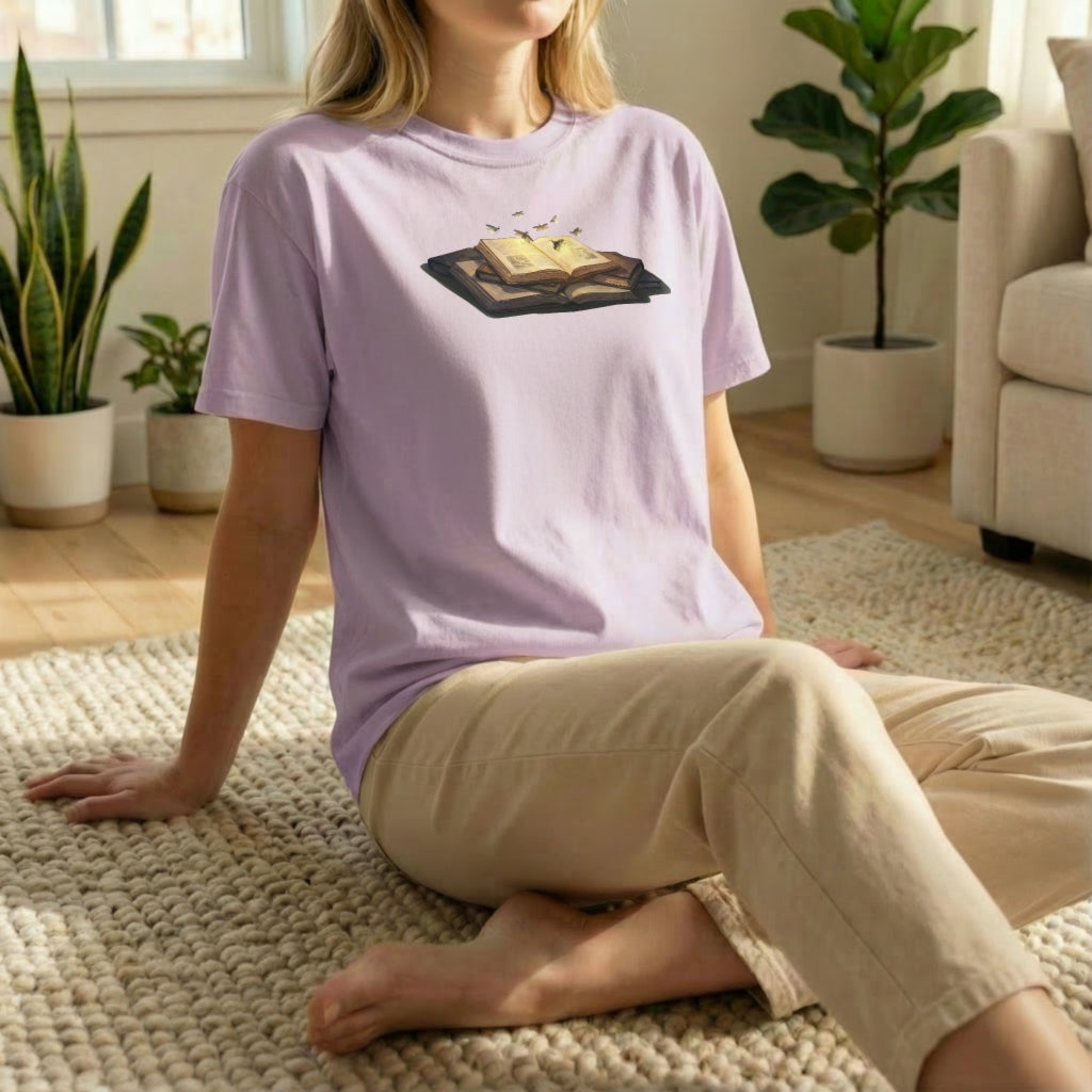 Firefly Book tee worn in relaxed floor pose on orchid shirt with cozy glowing book design