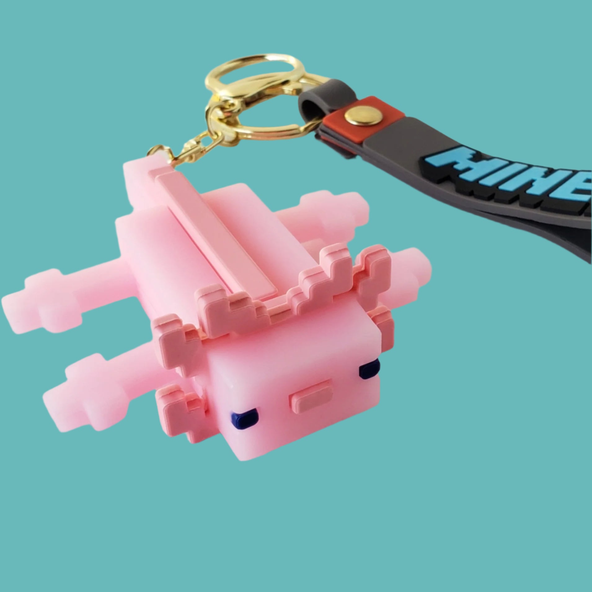 Close-up of Minecraft axolotl keychain showing pink pixel-style body and gold keyring with black Minecraft wrist strap