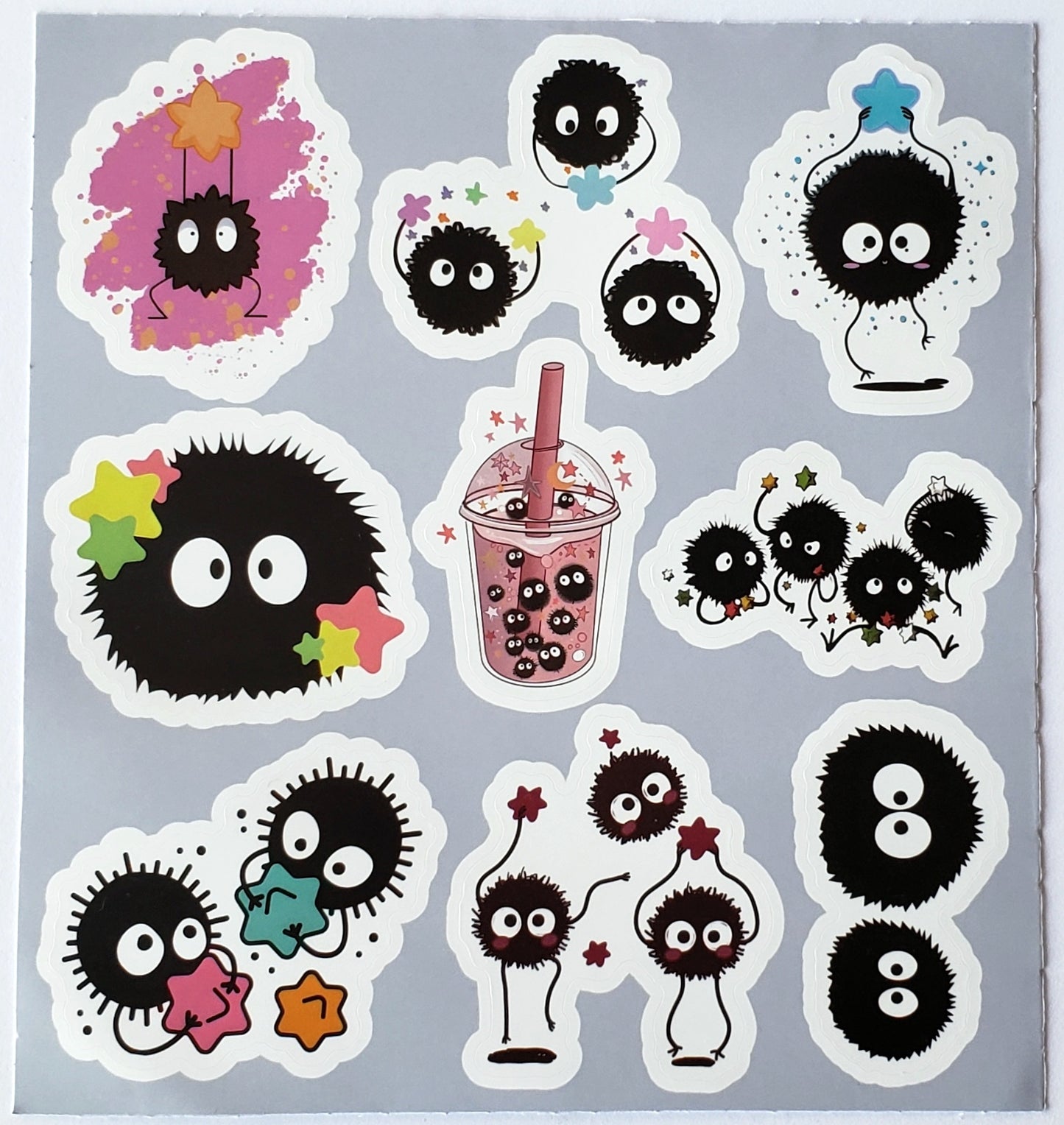 Flat-lay of the “Pink Smoothie Cup & Star Sprites” sticker sheet showing a central pink smoothie cup filled with soot sprites, surrounded by assorted soot sprites carrying colorful star accents on white die-cut backing.
