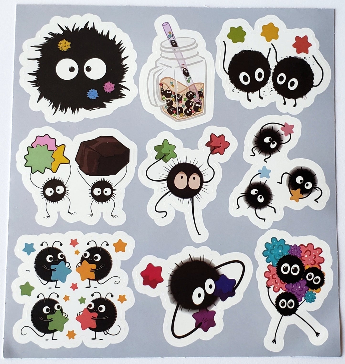 Flatlay of sticker sheet featuring soot sprites inside a mason jar, dancing duos, and scattered star clusters on a white background
