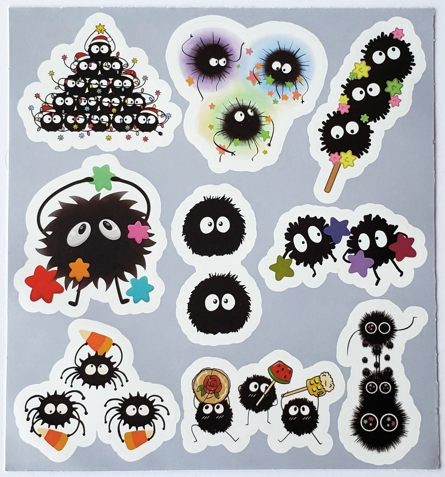 Flatlay of sticker sheet showcasing soot sprites in pyramid stacks, orbiting star formations, and swirling star garlands on a white background