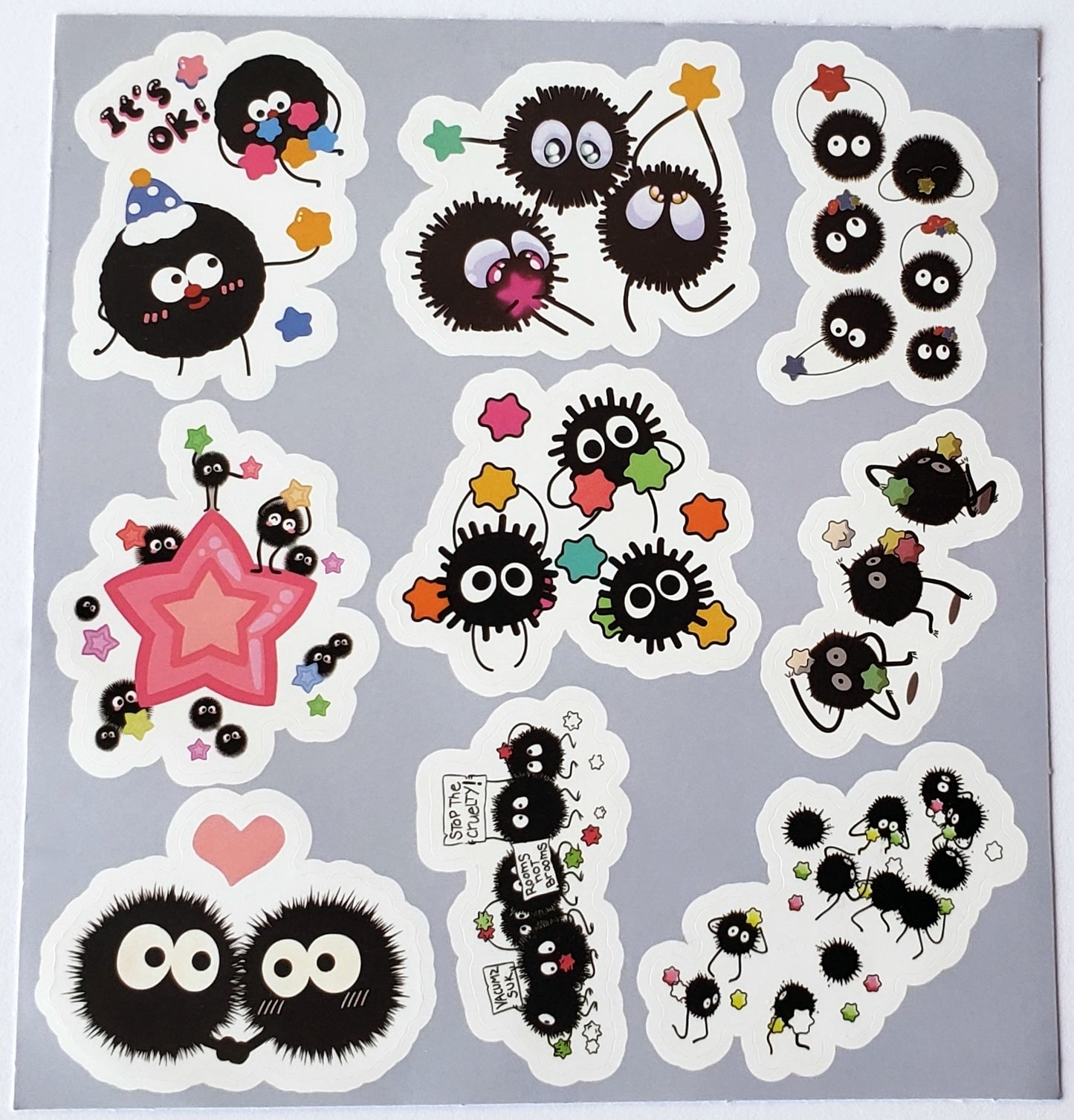 Flatlay of sticker sheet with soot sprites sharing stars, and carrying protest signs amid tiny stars on a white background