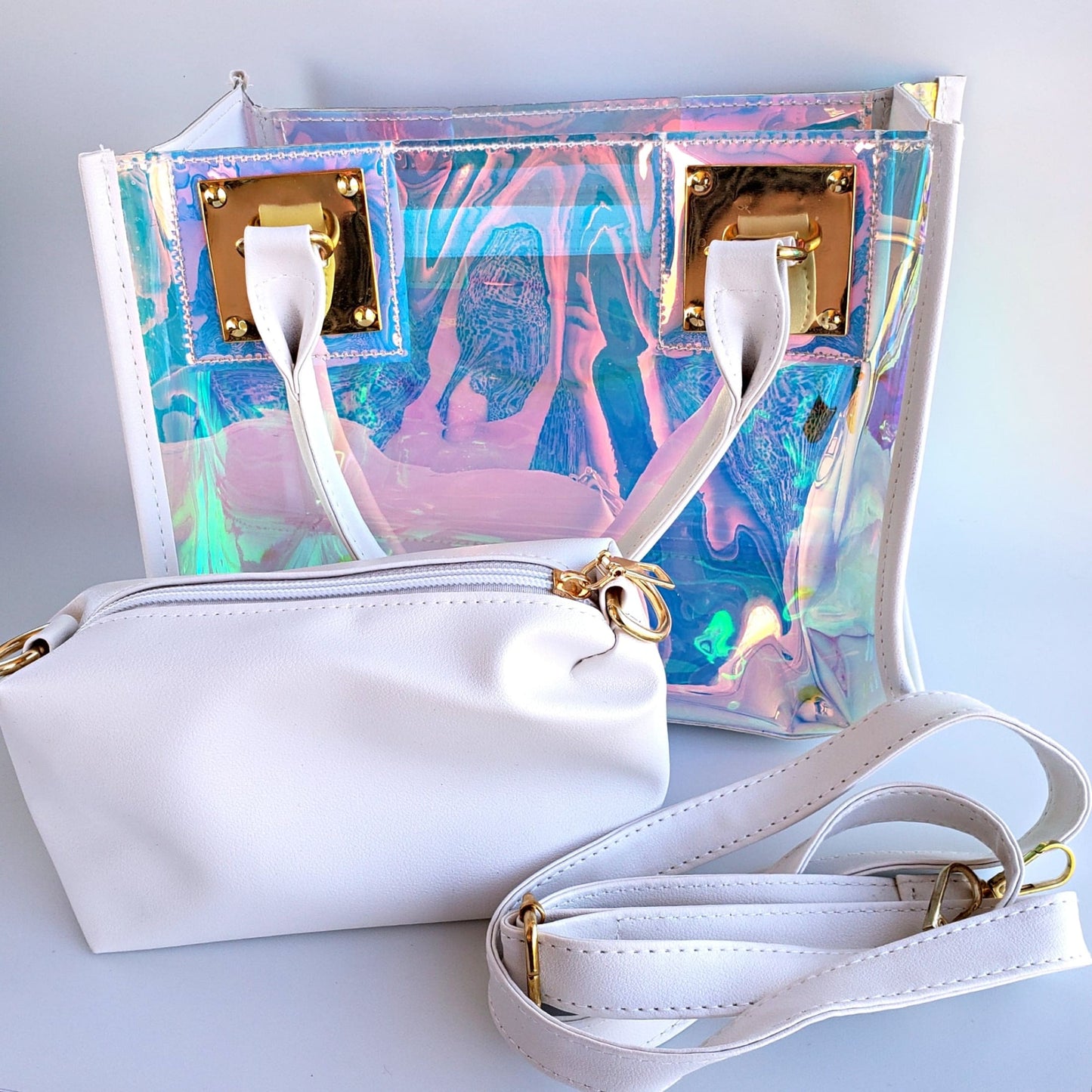 Iridescent transparent shoulder bag with white handles, gold trim showing blue and pink swirls