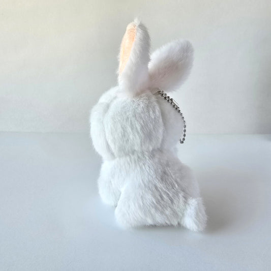 Back view of white bunny plush keychain highlighting its fluffy tail and ball-chain attachment against a white background