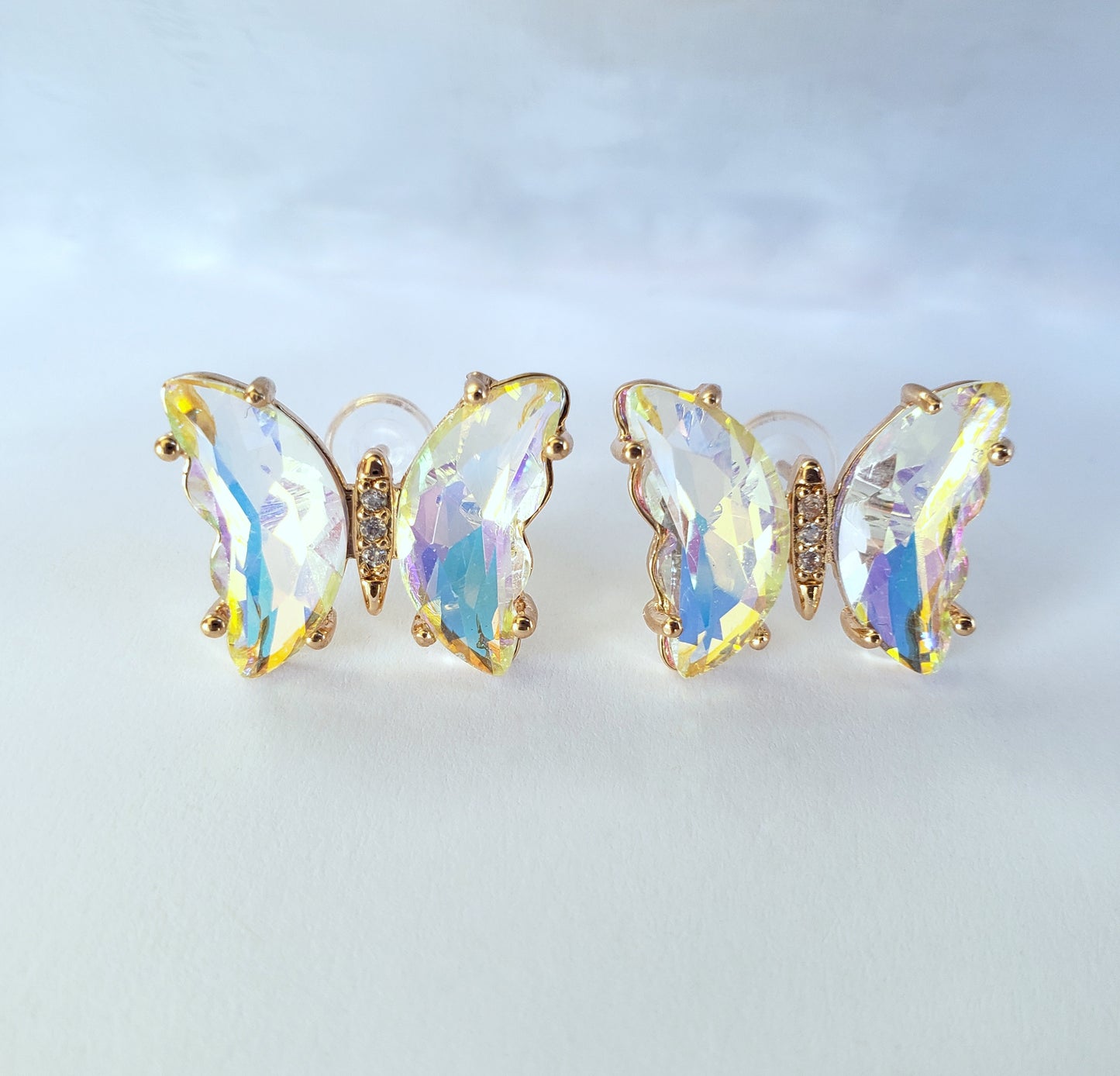 Crystal butterfly stud earrings in gold iridescent color on white background