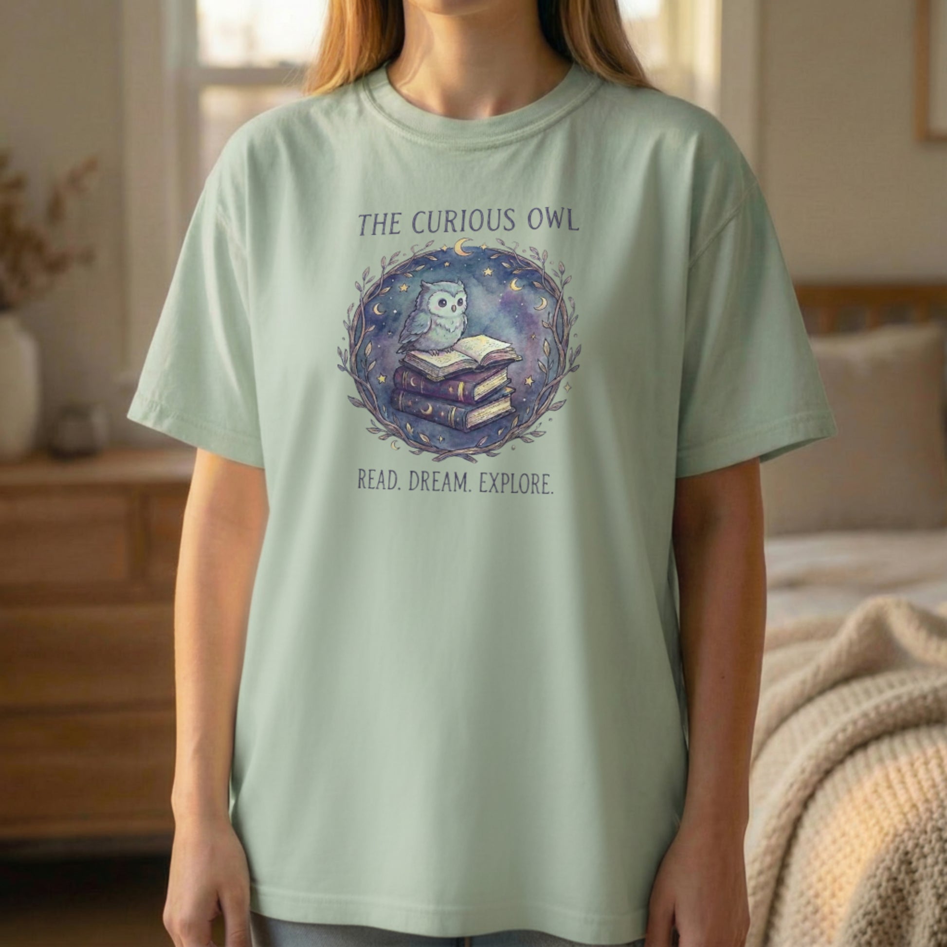 Front view of the Curious Owl tee on a sage Comfort Colors 1717 shirt with the owl reading books design