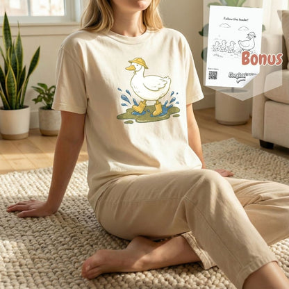 Woman sitting on a rug wearing an ivory duck t-shirt, shown with a free bonus digital coloring page bundle included with purchase.
