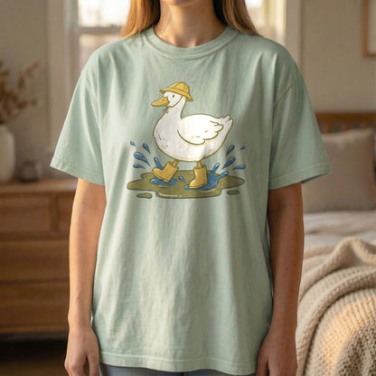 Mockup of a woman standing and wearing a light green t-shirt with a vintage illustration of a white duck in yellow rain boots.