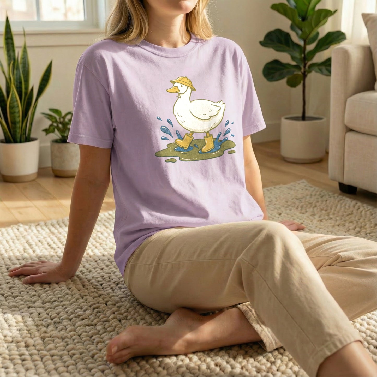 Woman sitting on a rug on the floor wearing an orchid purple t-shirt with a vintage duck and puddle design.