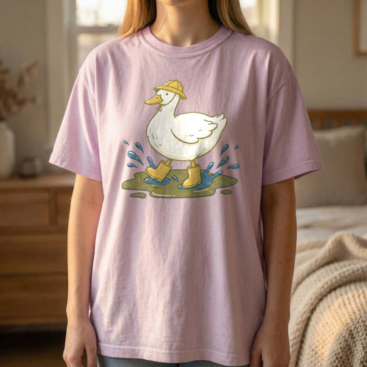 Mockup of a woman standing and wearing an orchid purple t-shirt with a vintage illustration of a white duck in yellow rain boots.