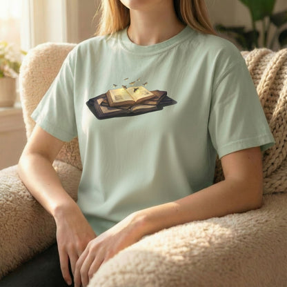 Firefly Book tee worn sitting on couch on light green shirt with soft glowing book design