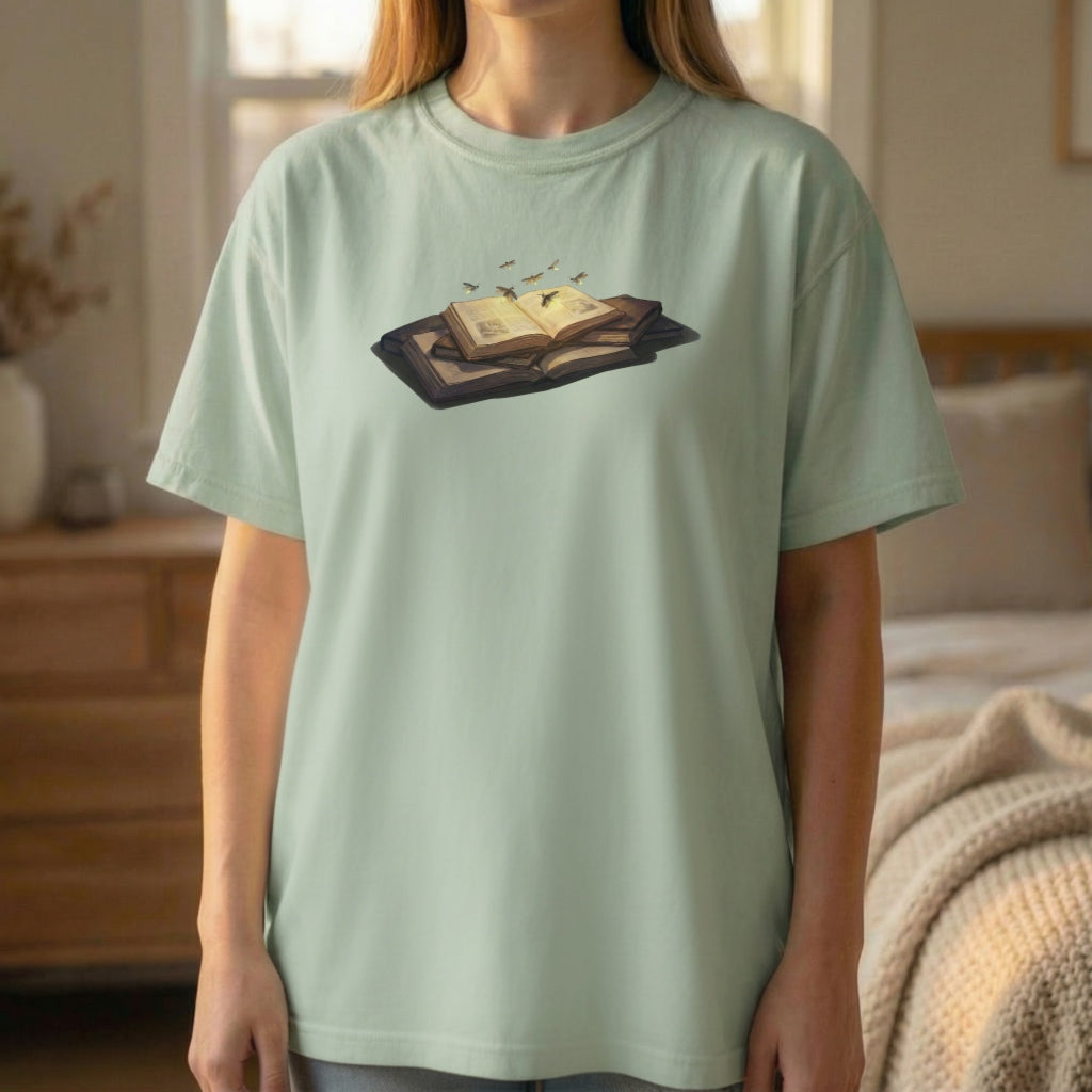 Firefly Book tee worn standing on light green shirt with glowing firefly book illustration