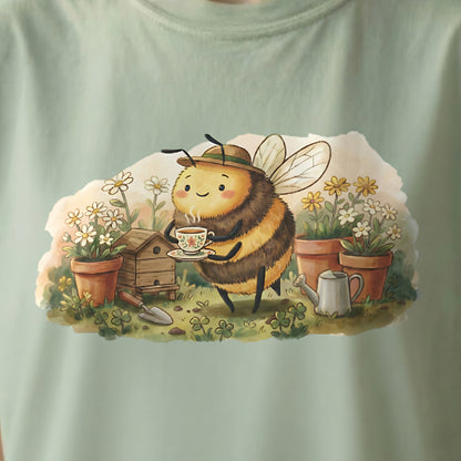 Close-up view of Garden Bee Tee design on light green shirt featuring cozy bee garden illustration