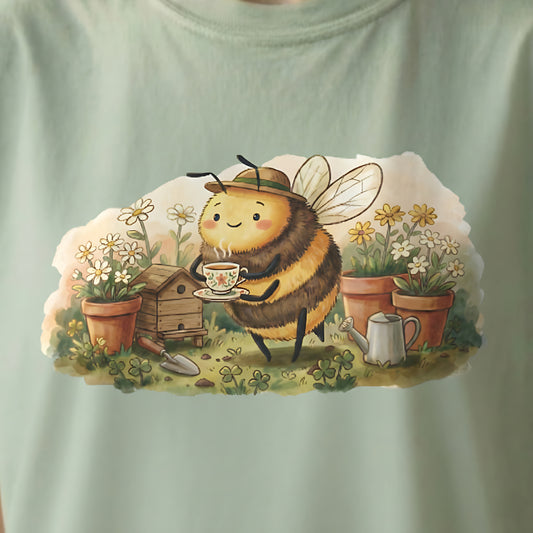 Close-up view of Garden Bee Tee design on light green shirt featuring cozy bee garden illustration