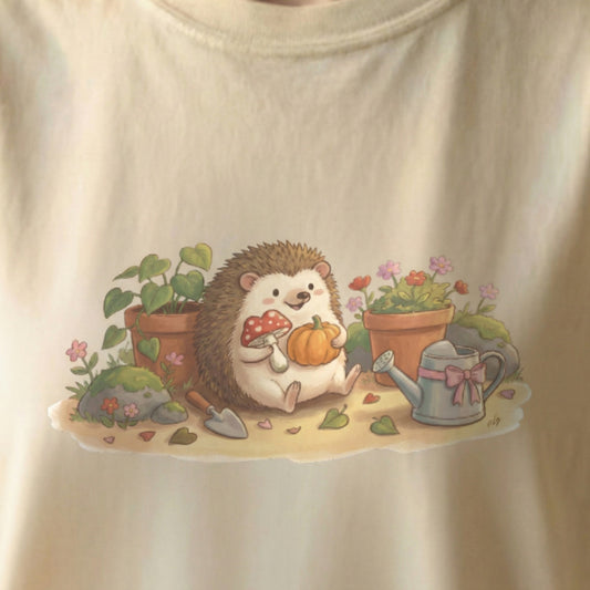Close-up of Garden Hedgehog tee artwork featuring a cozy hedgehog surrounded by flowers and garden details