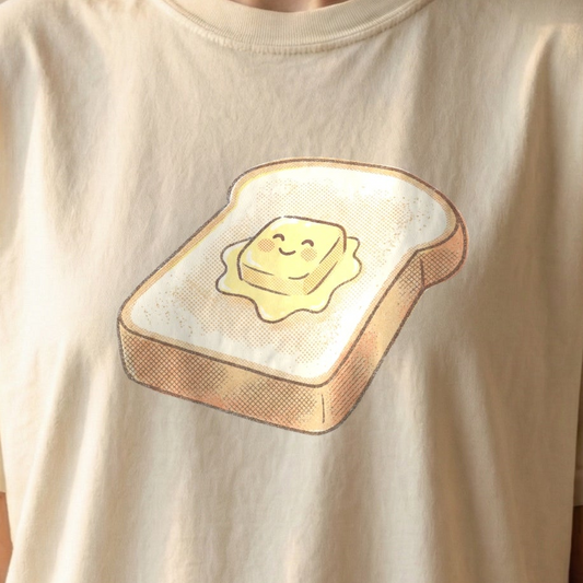 Happy Morning Toast Tee on ivory Comfort Colors shirt featuring smiling cartoon toast with butter pat sitting on plate, vintage-style kawaii design for slow morning lovers.