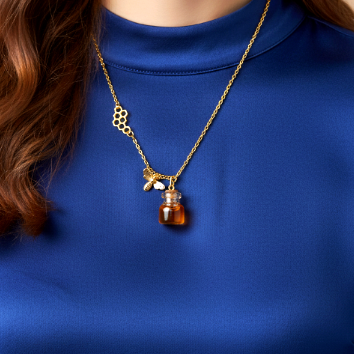 Honey jar necklace with golden bee charm and honeycomb detail shown on model wearing blue top