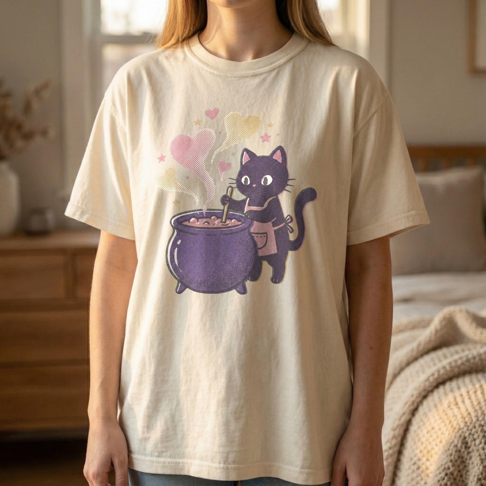 Mockup of a woman standing wearing an ivory t-shirt with a pixel art black cat in an apron stirring a purple cauldron.