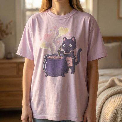Mockup of a woman standing wearing an orchid t-shirt with a pixel art black cat and purple cauldron design.