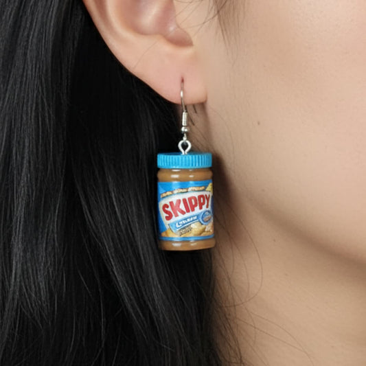 Close-up of peanut butter jar earrings with blue lid worn on ear