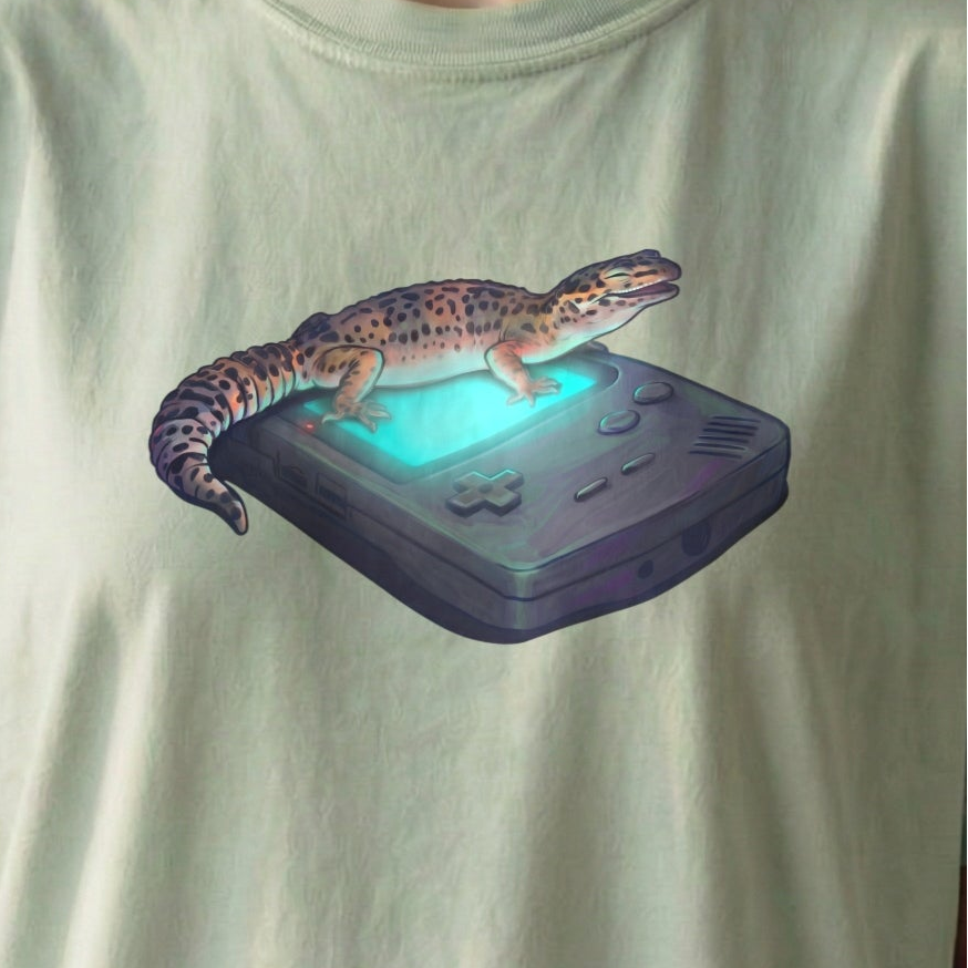 Close-up of Retro Gecko tee artwork featuring a gecko resting on a glowing retro handheld console