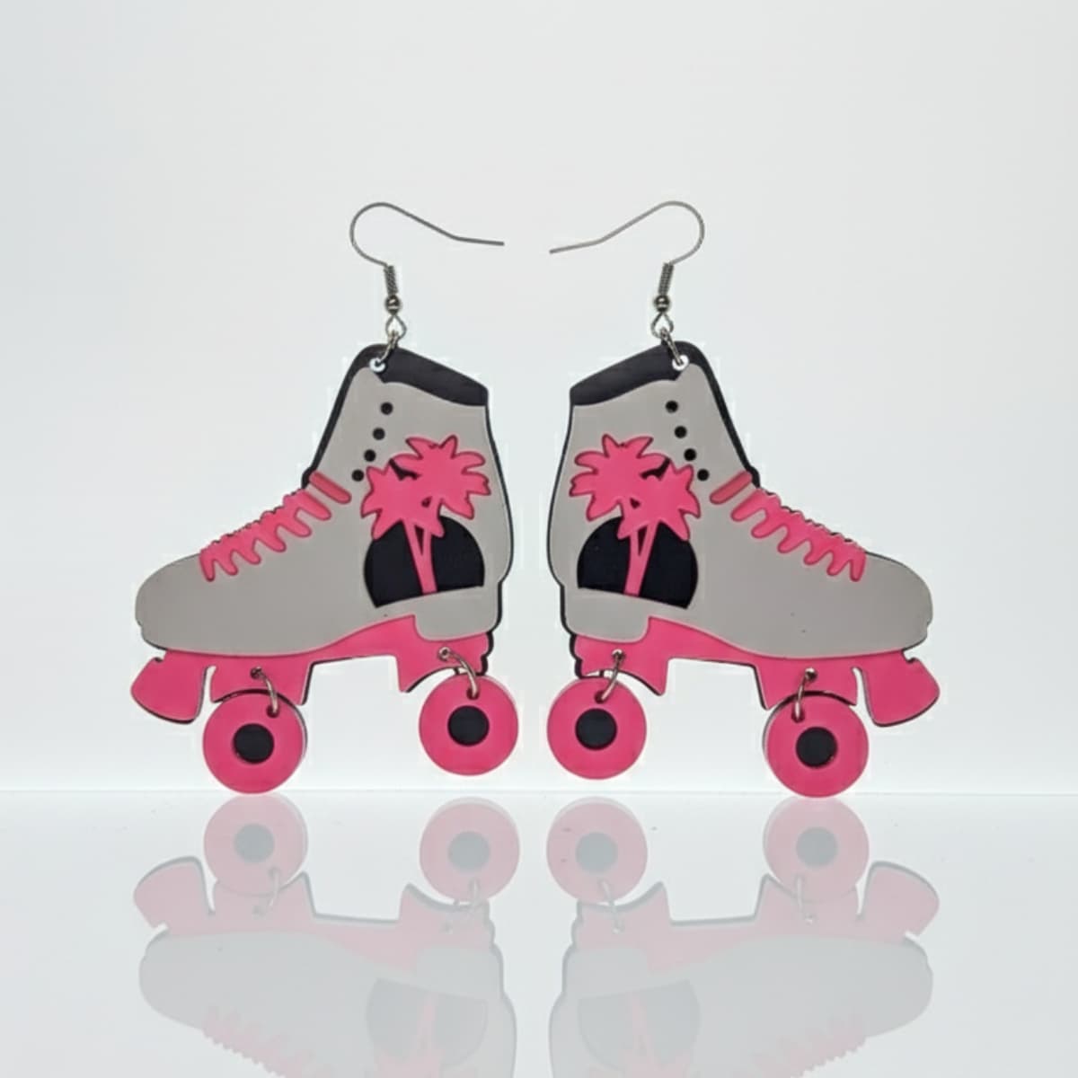 Pair of white and pink roller skate dangle earrings, flatlay on white background