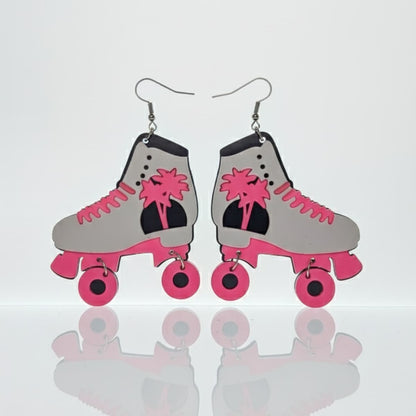 Pair of white and pink roller skate dangle earrings, flatlay on white background