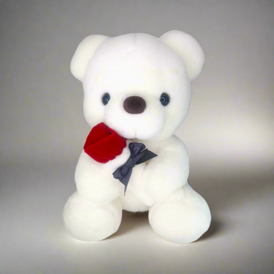 white bear plush sitting upright holding a red rose against a studio background