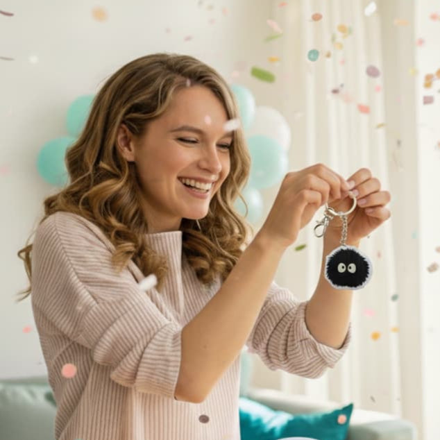 Smiling woman holding a Soot Sprite acrylic keychain indoors