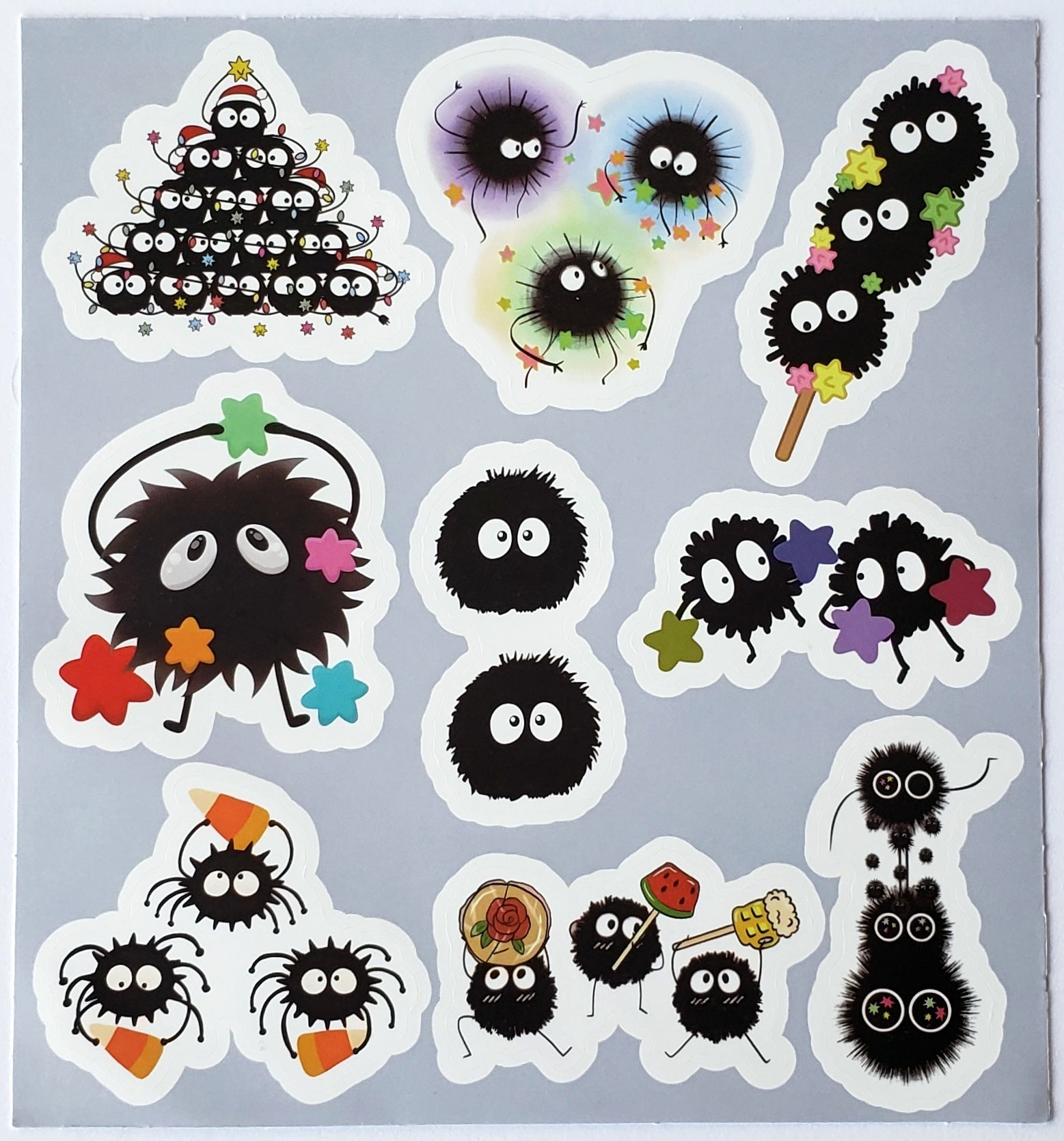 Flatlay of sticker sheet showcasing soot sprites in pyramid stacks, orbiting star formations, and swirling star garlands on a white background