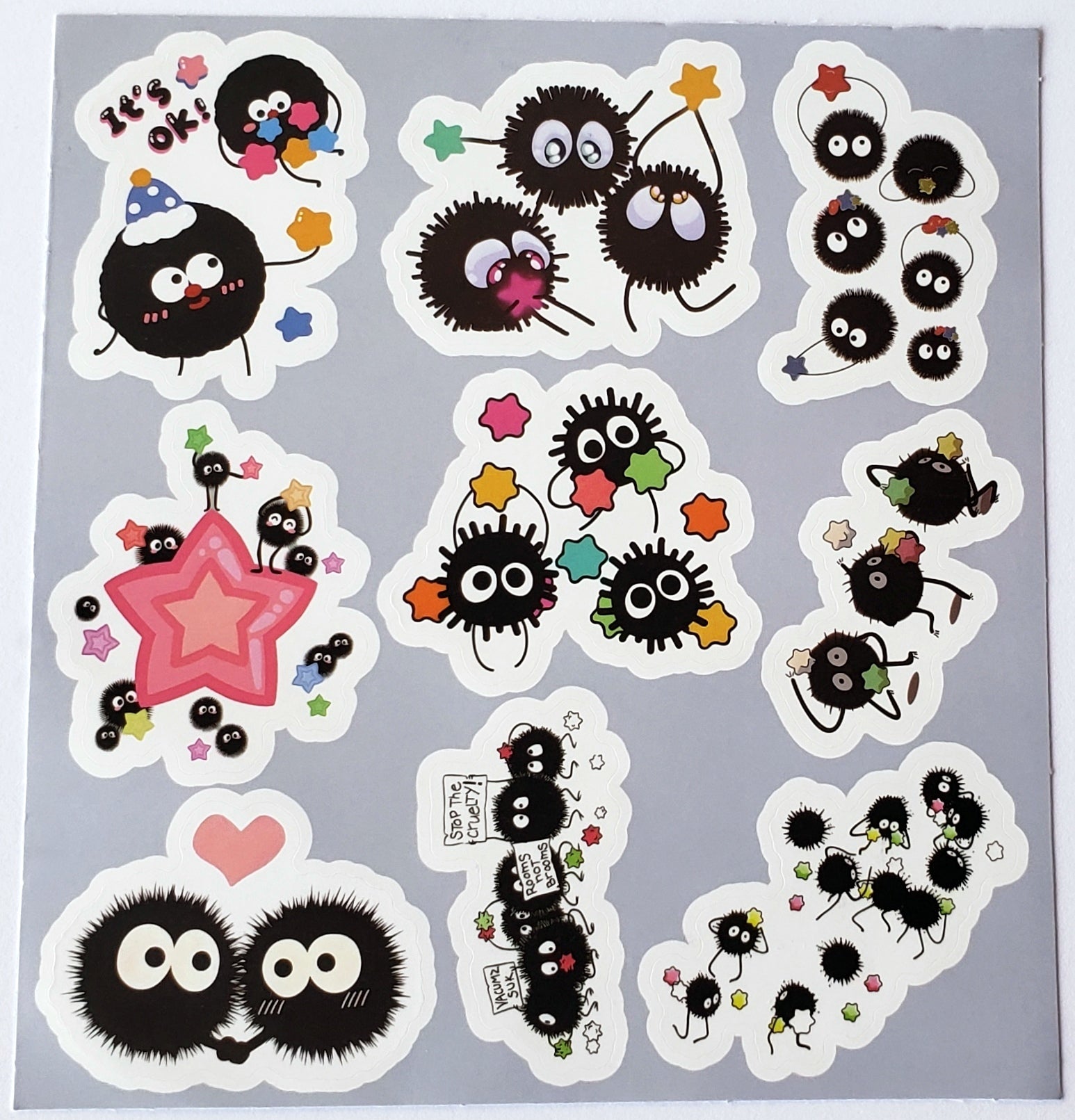 Flatlay of sticker sheet with soot sprites sharing stars, and carrying protest signs amid tiny stars on a white background