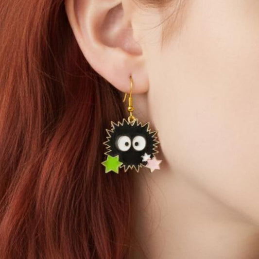 Close-up of black sprite acrylic earrings with green and pink stars worn on ear