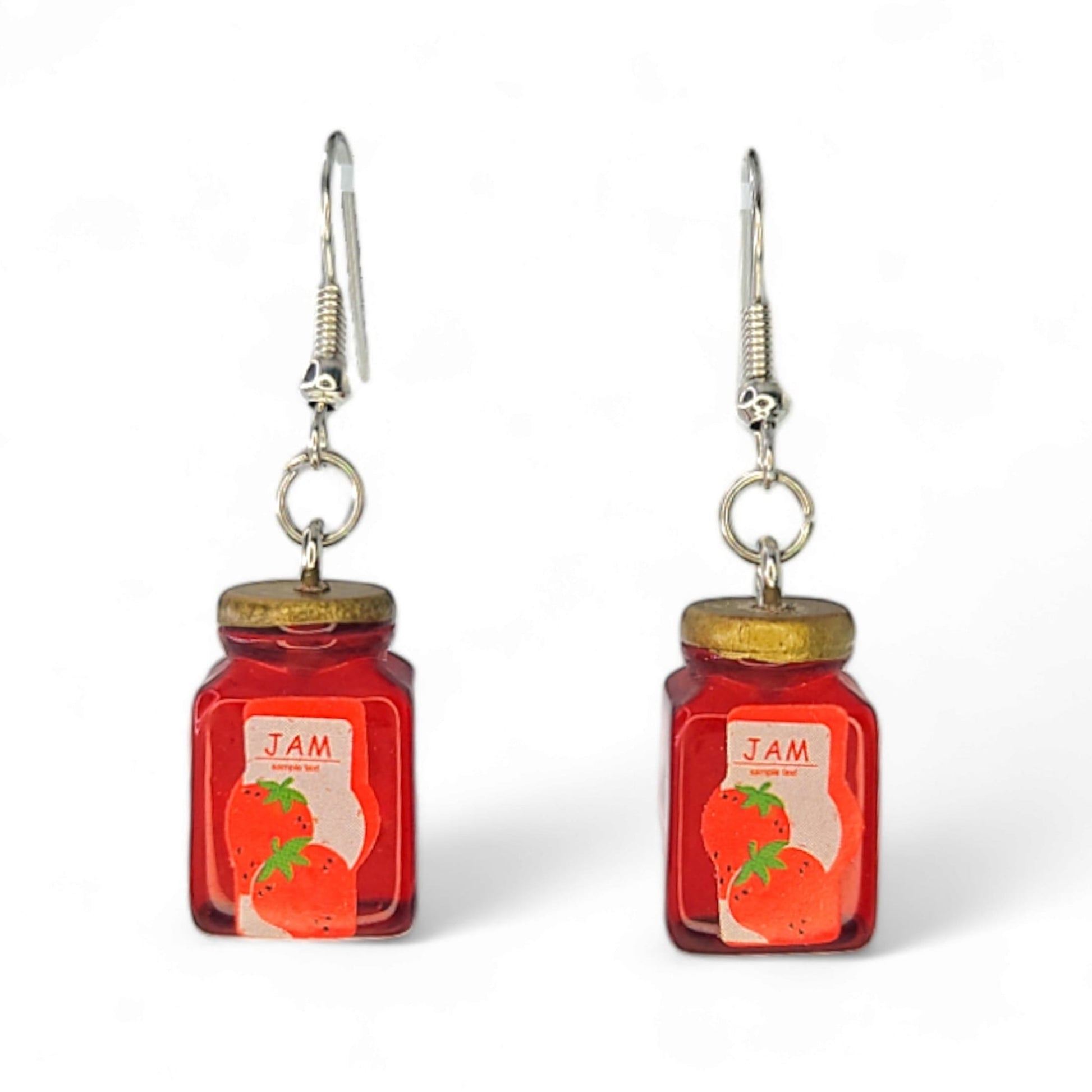 Close-up of tiny strawberry jam jar charms with glossy red detail on dangle hooks