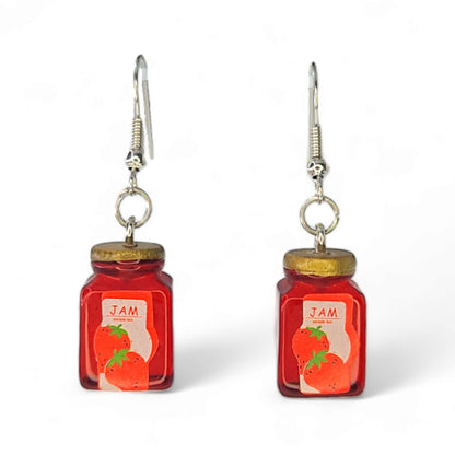 Close-up of tiny strawberry jam jar charms with glossy red detail on dangle hooks