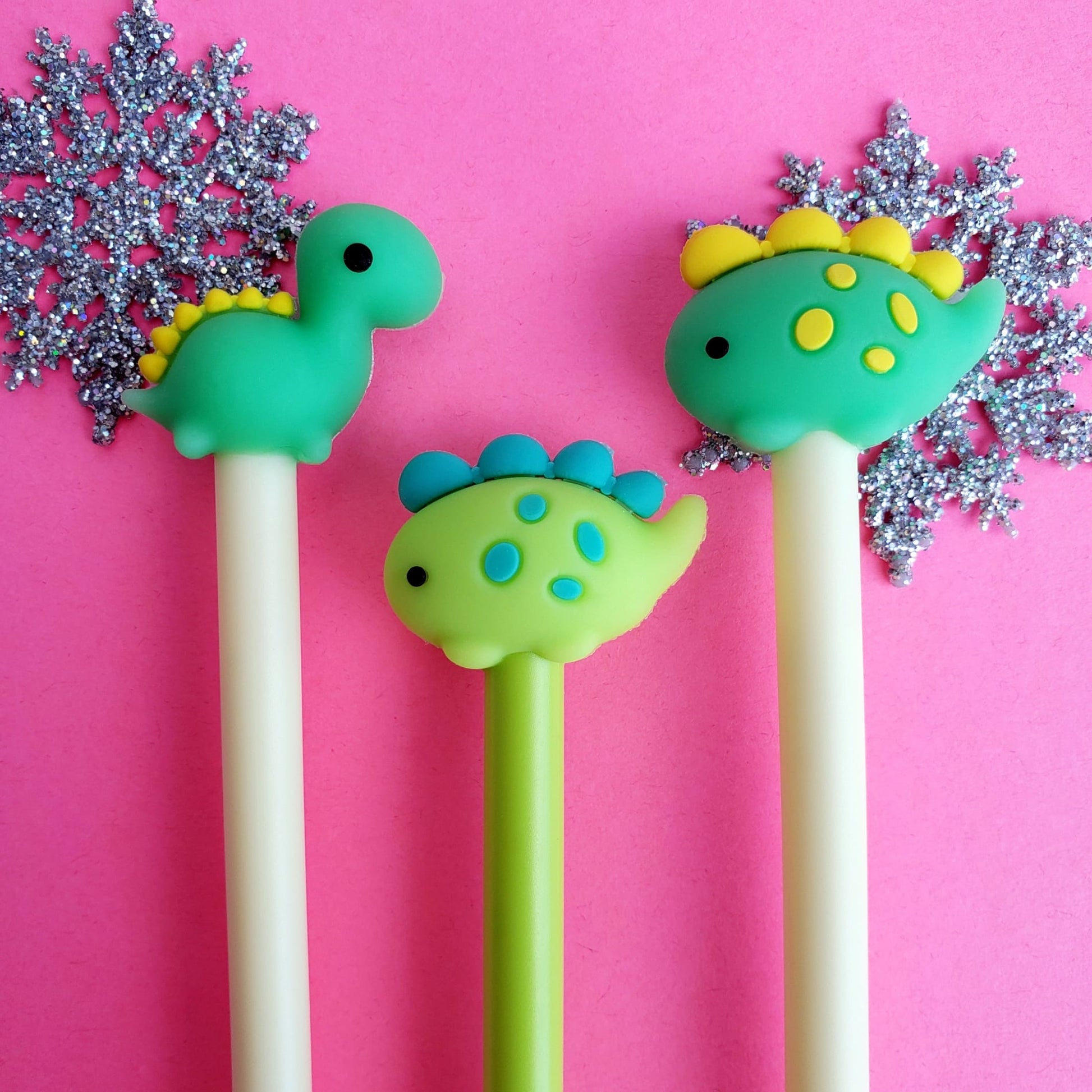 Close-up of dinosaur pen toppers on a pastel pens, decorative background